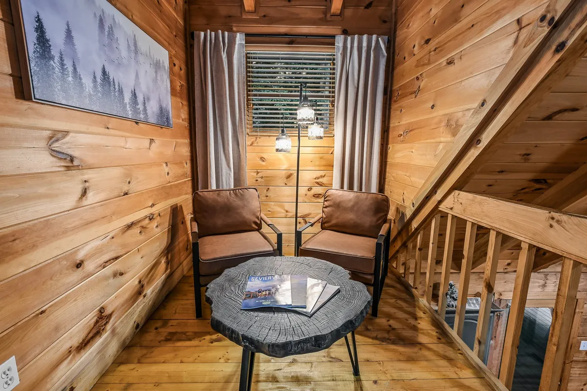 A welcoming dining or gathering space featuring rustic wooden walls, circular table, comfortable chairs, and soft lighting fixtures. The open, homey setting encourages conversation and relaxation, evoking the communal spirit of après-adventure evenings or summer gatherings.