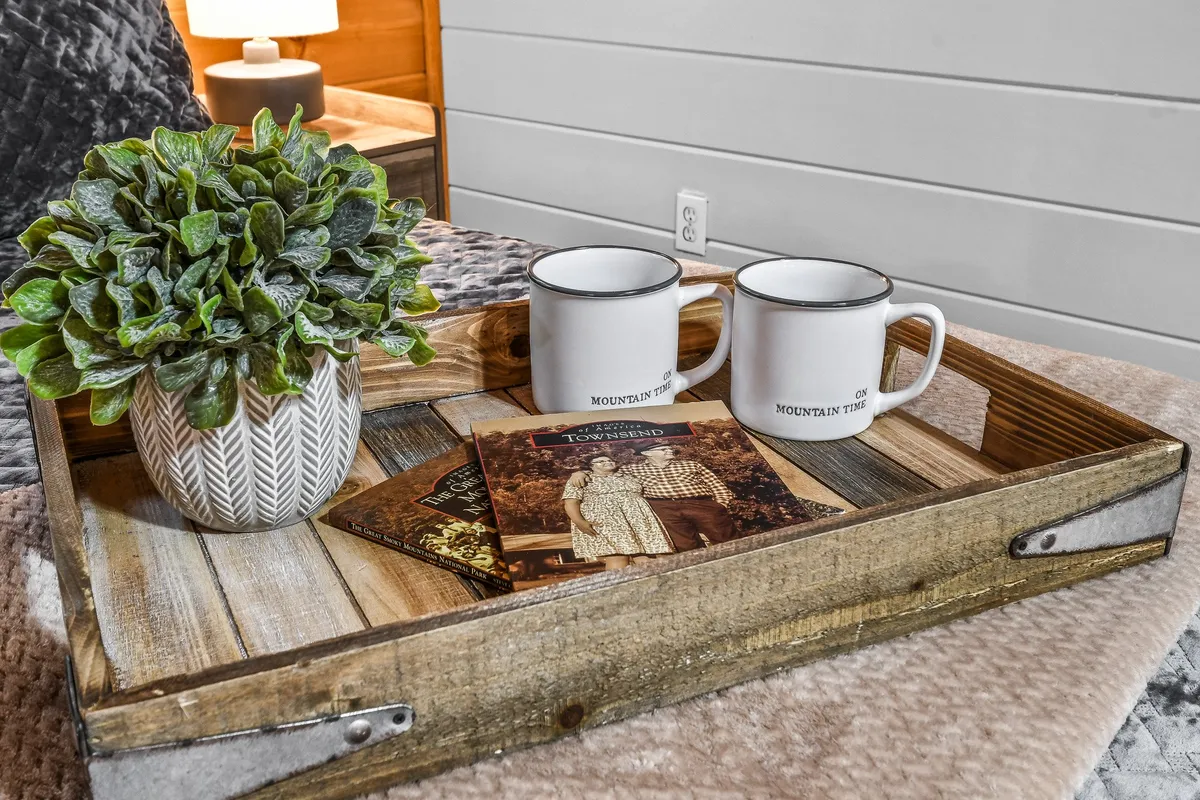 A close-up of a wooden tray set with mugs and a potted plant, surrounded by personal photographs, creating an ambiance of intimacy and comfort. The scene is set for quiet mornings or cozy evenings, suggesting meaningful conversations and moments shared over coffee.